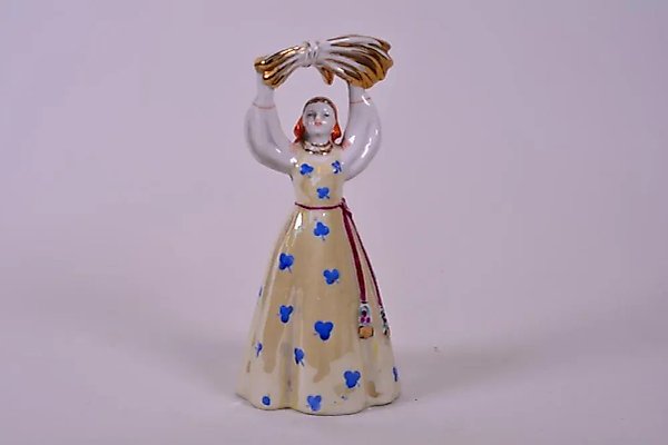 Фигурка колхозницы, держащей сноп пшеницы над головой, ручная роспись над глазурью, произведена на фарфоровой фабрике Дулево.