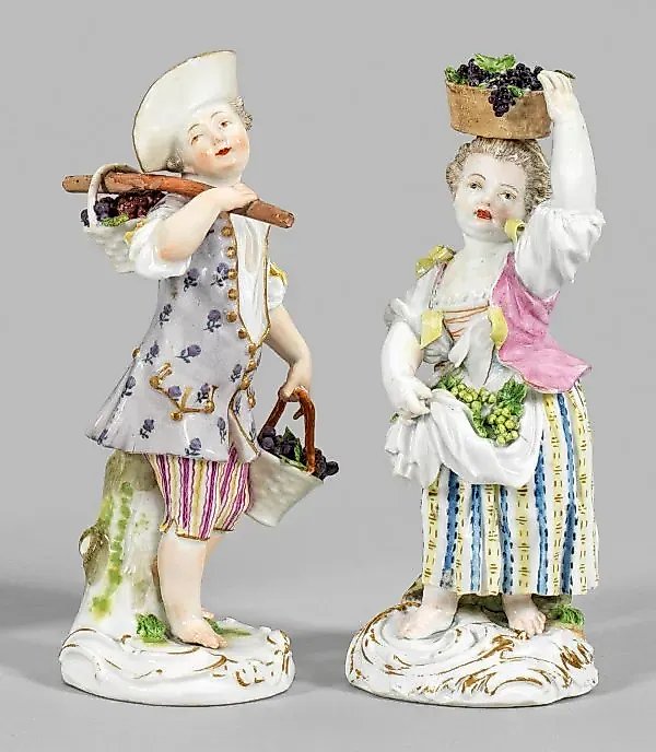 A pair of porcelain figures of gardeners with baskets of grapes