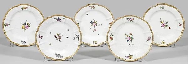 A collection of five porcelain plates with fruit and floral decor