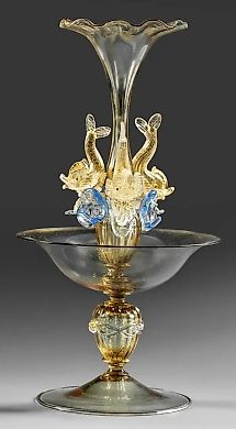 A richly articulated form on a single stem with a bell-shaped shell and three stylized dolphins