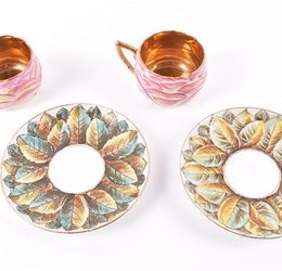 A pair of Imperial Russian Kuznetsov porcelain cups and saucers the cups modelled as blooming