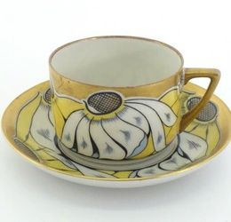 A Russian porcelain cup and saucer by the Dulevo factory in 1925, the design alternating yellow and white flower heads below the gilt rim. Blue Dulevo factory backstamp to underside of both pieces. In very good condition, no defects noted.
