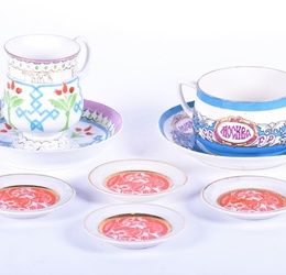 A Russian Kuznetsov porcelain cup and saucer with painted floral motifs and gilt highlights, both