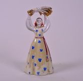 A 1960s Russian Dulevo factory porcelain figure of a traditional Soviet girl holding a wheatsheaf over her head, hand painted over glaze, stamped to base, 6" high x 3" wide