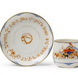A porcelain cup and saucer decorated with printed agricultural propaganda motifs. Showing peasants