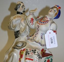 A Kiev Russian porcelain figure group, modelled as a man and woman in national costume seated on a